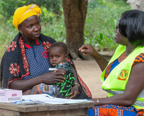 A mother and her 2 year old son are attended to by a community health volunteer in Cote d'Ivoire