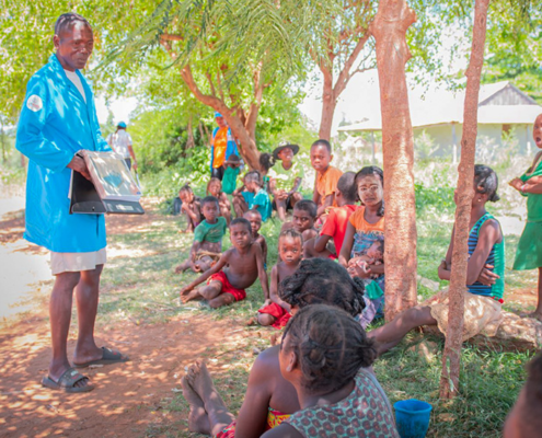 A male community health volunteer conducts a mass education session on the use of mosquito bed nets in Madagascar