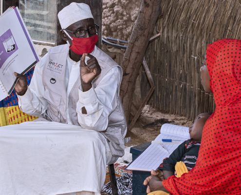 A male community health worker in Niger talks with a mother about the best ways to protect herself and her family from malaria
