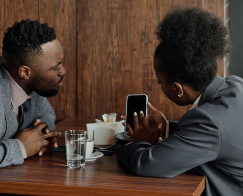 Two people sitting in café looking at a phone together