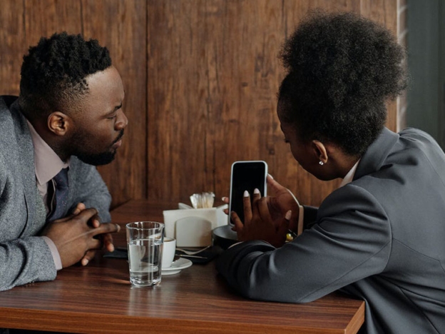 Two people sitting in café looking at a phone together