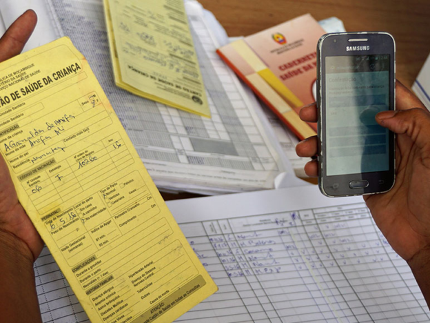 A female health worker uses a mobile app to record vaccination data in Mozambique