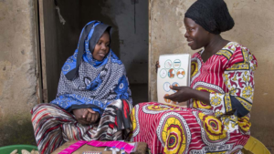Female community health worker talks to a woman during a home visit in Uganda