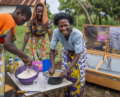 Three women preparing to bake cakes with a solar oven in Mombasa, Kenya