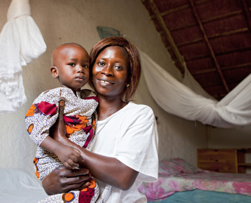 A Senegalese mother and child with knotted bed nets in the background