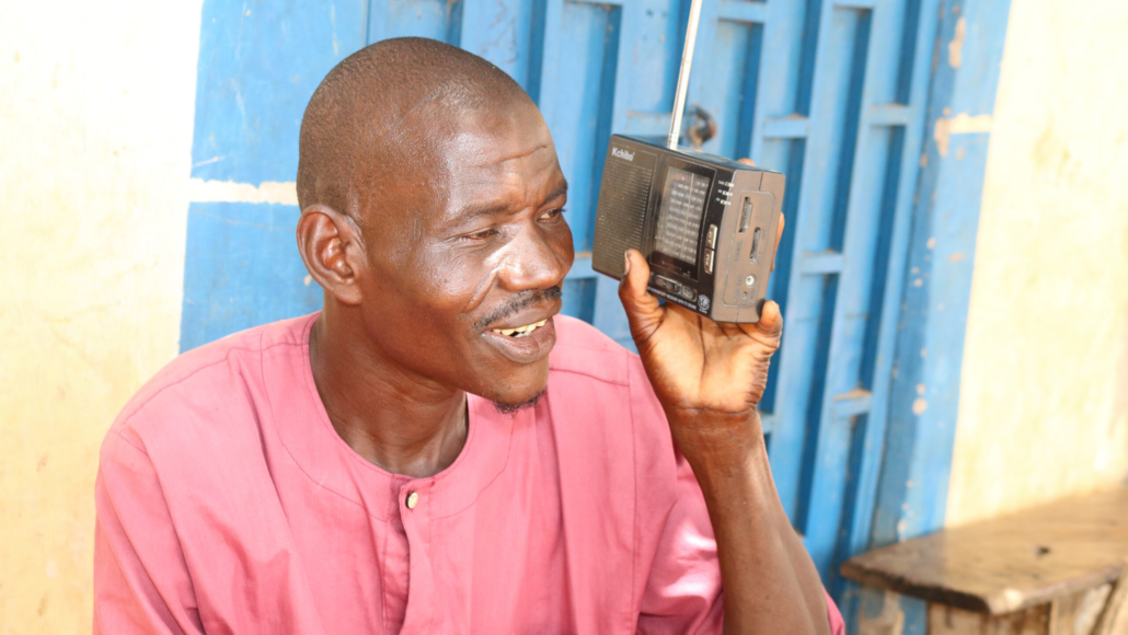 A man listening to a handheld radio in Kebbi State, Nigeria
