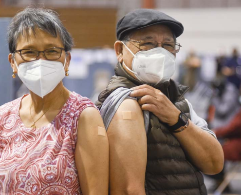 Two older adults with surgical masks and bandages after getting vaccinated in New York City